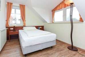 A bedroom with a bed, a nightstand, a lamp, and a window with curtains.