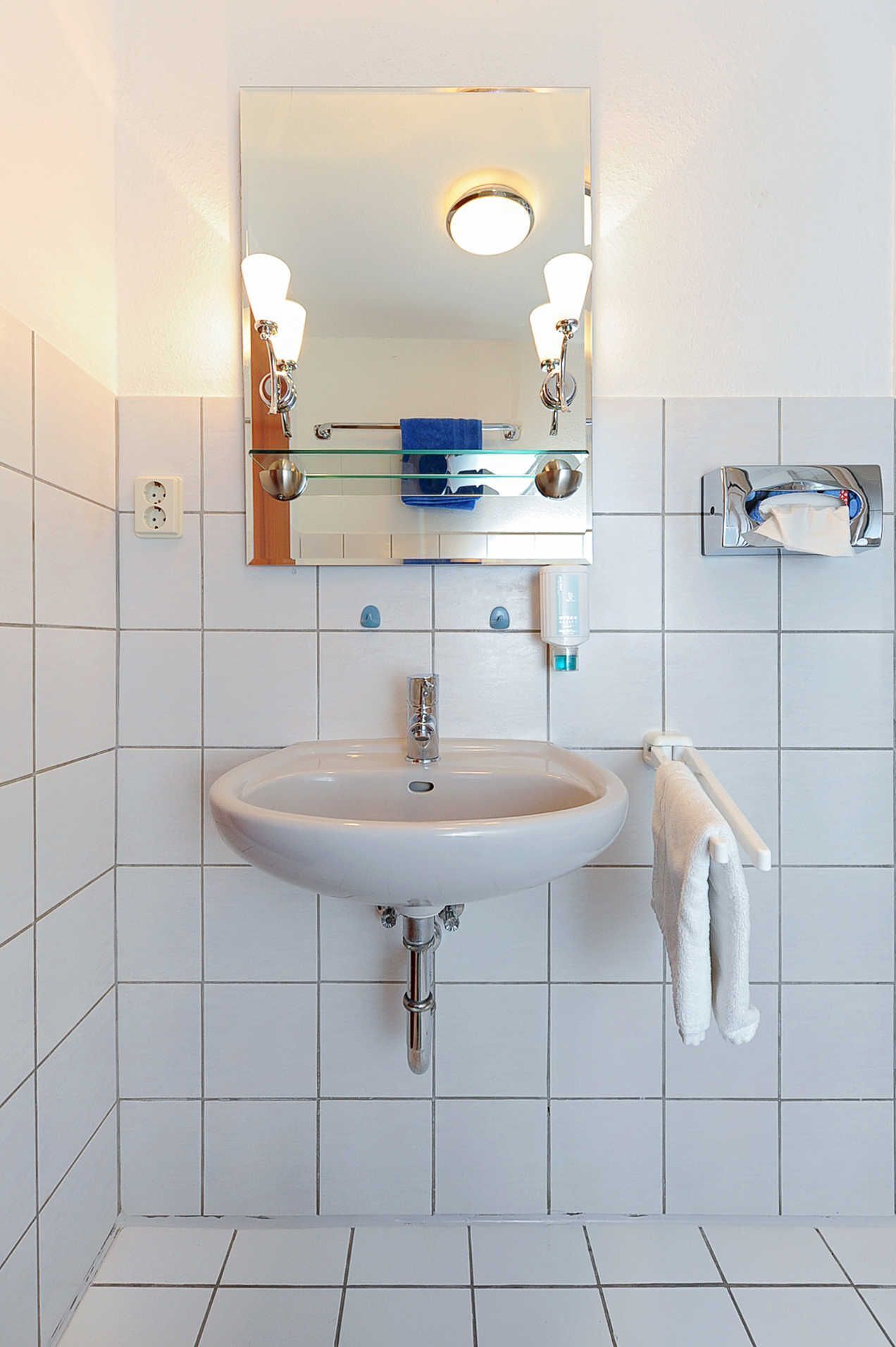 Een badkamer met een witte wastafel, een spiegel en een handdoekhouder.