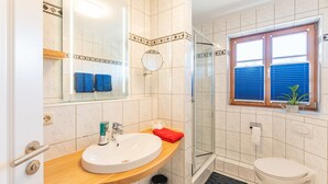 A bathroom with a sink, mirror, shower, and toilet.