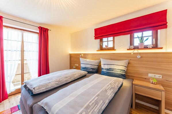 A double bed with striped bedding, a wooden headboard, and a red valance.