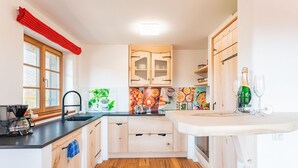 A modern kitchen with wooden cabinets, a black countertop, and a wooden floor.