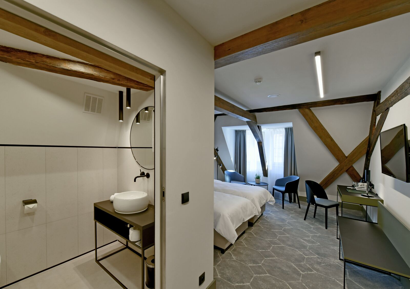 Ein modernes Hotelzimmer mit Bad, einem Bett, einem Schreibtisch und Blick nach außen.