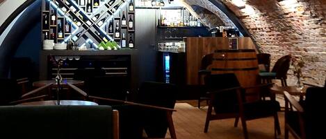 An interior with a vaulted brick ceiling, wooden furniture, and a bar area with bottles and glasses.