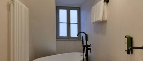 A modern bathroom with a freestanding bathtub, a sink, and a window providing natural light.