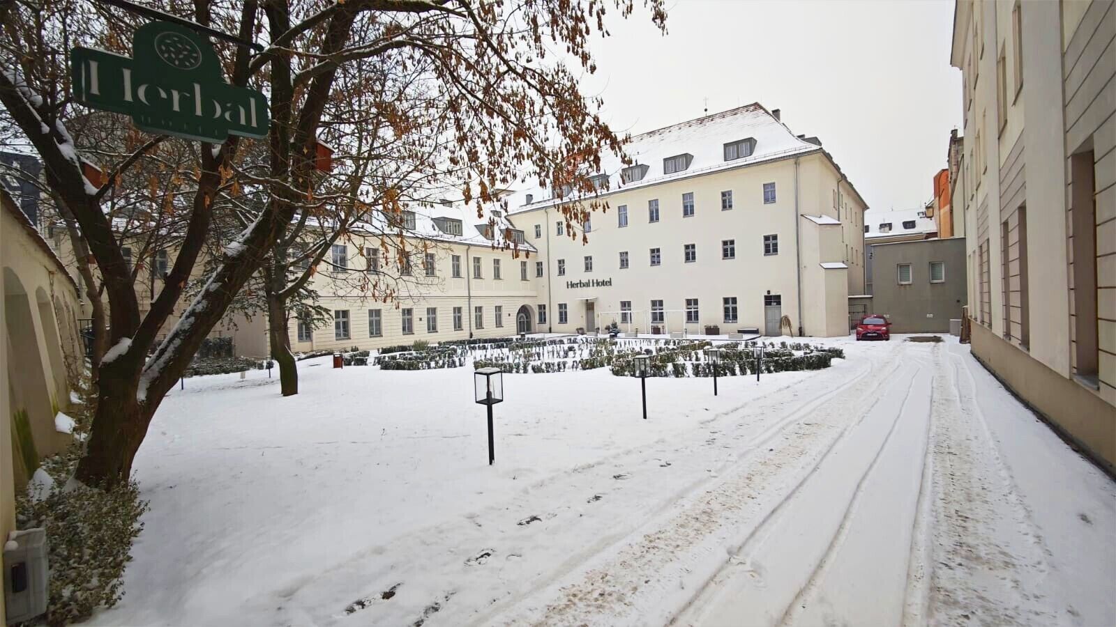 A snow-covered street with a building labeled "Herbal Hotel" in the background.