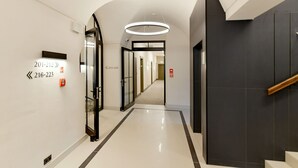 A modern hotel corridor with directional signs, a glass door, and a staircase. - Herbal Hotel (Wroclaw)