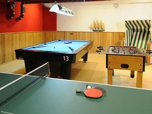 Une table de billard portant le numéro 13, une table de baby-foot et une table de ping-pong.