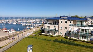 A marina with boats, a building with balconies, and a clear sky.