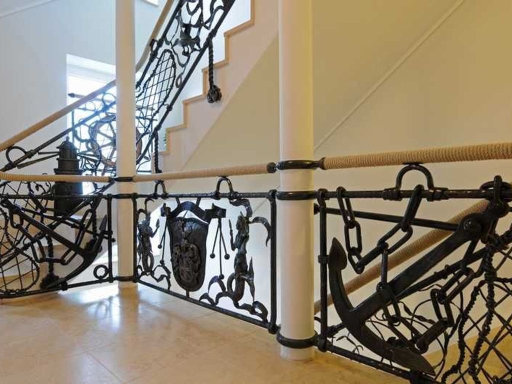 Eine Treppe mit aufwendigen schwarzen Metallgeländern und einer weißen Säule.