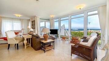 A spacious living room with a large window, a television, and a sailboat model.