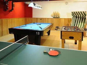 Une table de billard portant le numéro 13, une table de baby-foot et une table de ping-pong.
