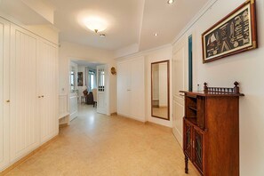 Un pasillo con puertas blancas, un armario de madera y un cuadro en la pared.