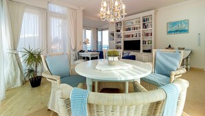 A living room with wicker furniture, a chandelier, a bookshelf, and a painting. - Ut Mine Stromtid mit Kinderzimmer - Strandresidenz-kühlungsborn (Kühlungsborn)