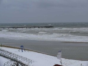 A snowy beach with a pier extending into the water.