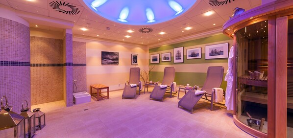Une salle de spa avec un éclairage au plafond, des fauteuils inclinables, une table de massage et des tableaux encadrés accrochés au mur.