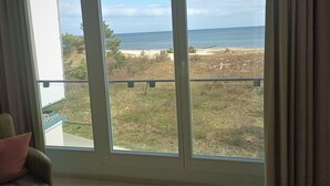 Ein Zimmer mit großem Fenster und Blick auf einen Strand.