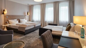 Et hotelværelse med to senge, en sofa, et spisebord og et dekorativt bakkesæt.