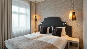 Et hotelværelse med en stor seng, to sengeborde og en tapetvæg.