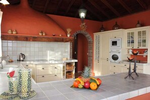 Eine Küche mit weißen Schränken, einer gefliesten Spritzschutzwand und einer Obstschale auf der Arbeitsplatte.