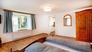Un dormitorio con una cama de madera, una ventana con cortinas, un espejo y un armario de madera.