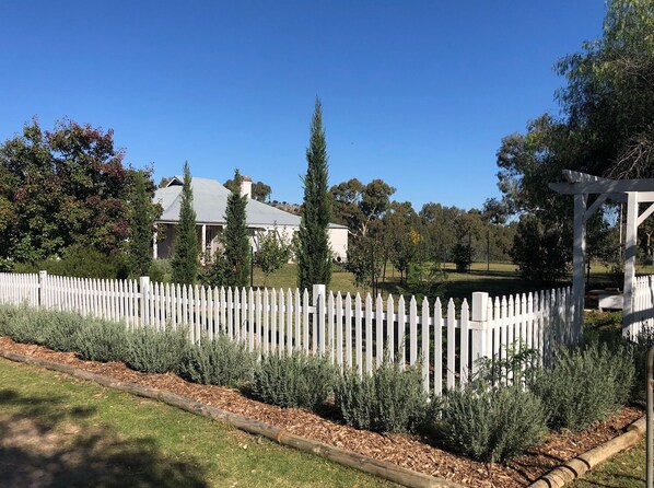 Une propri été résidentielle avec une clôture en bois peinte en blanc, un jardin bien entretenu et une maison avec un toit gris.