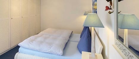 Un dormitorio con cama, lámparas de noche, armario y espejo.