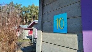 Un edificio con un cartello con il numero 10 su una parete di legno, un portico coperto e vista sulle case vicine.