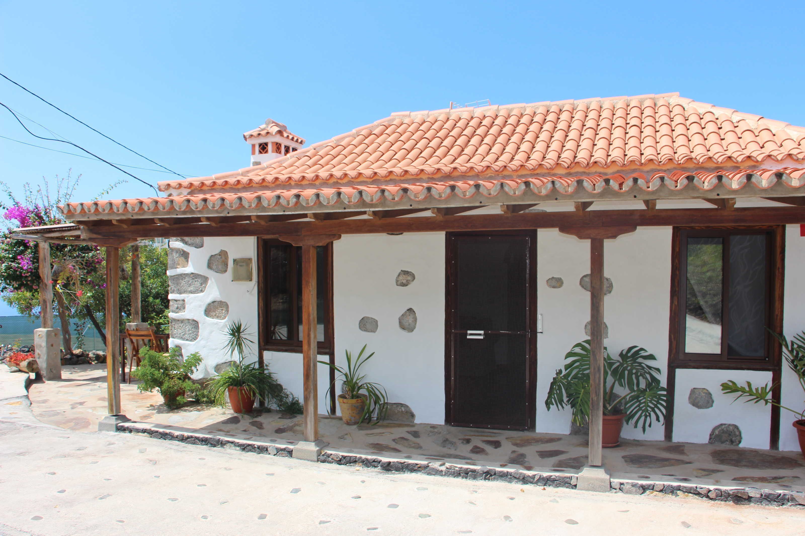 A small, single-story building with a tiled roof, stone walls, and a wooden porch.