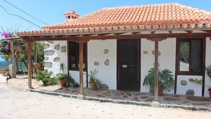 Un edificio pequeño de una sola planta con tejado de baldosas, paredes de piedra y porche de madera.