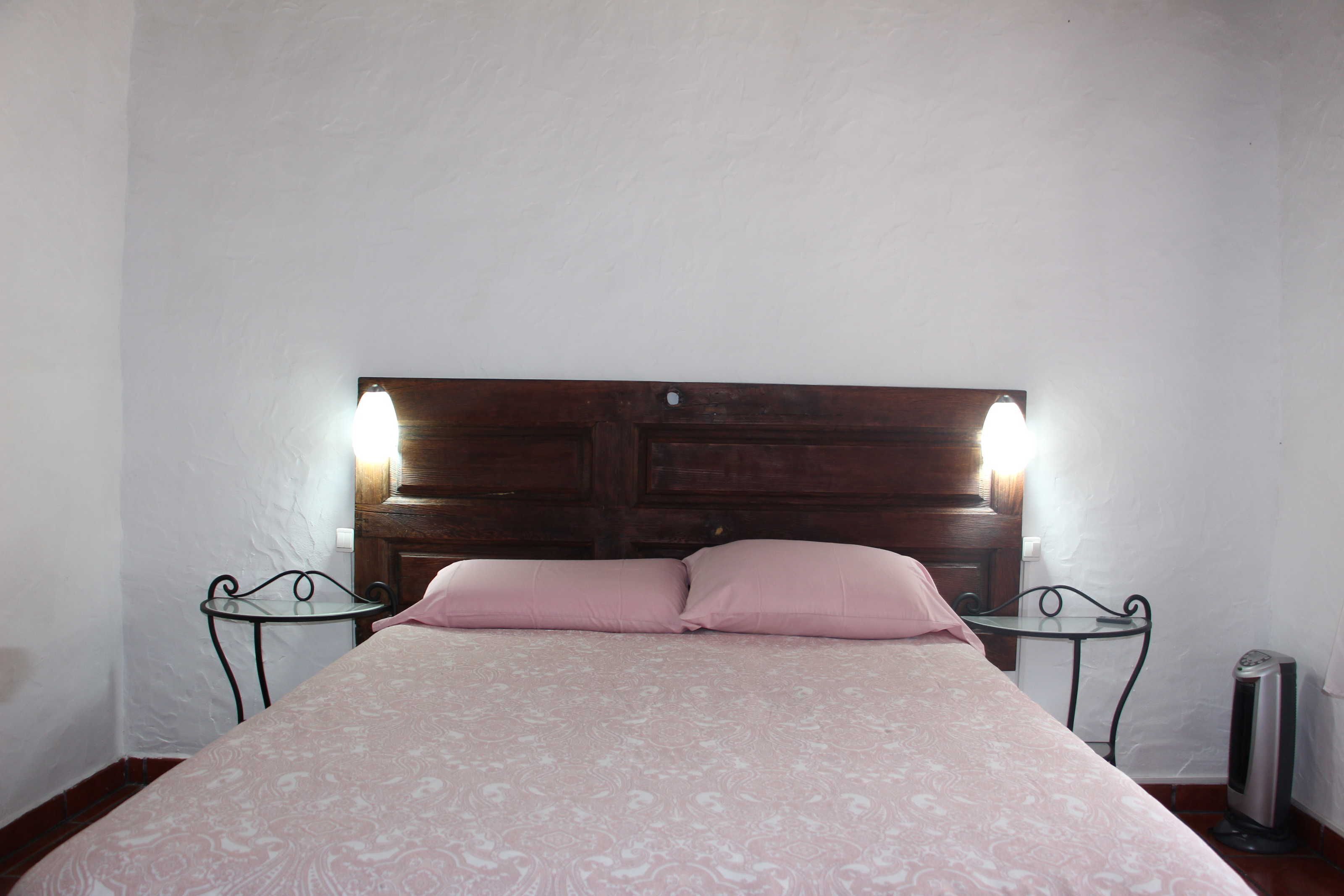 Un lit avec une tête de lit en bois, deux tables de chevet et un radiateur.