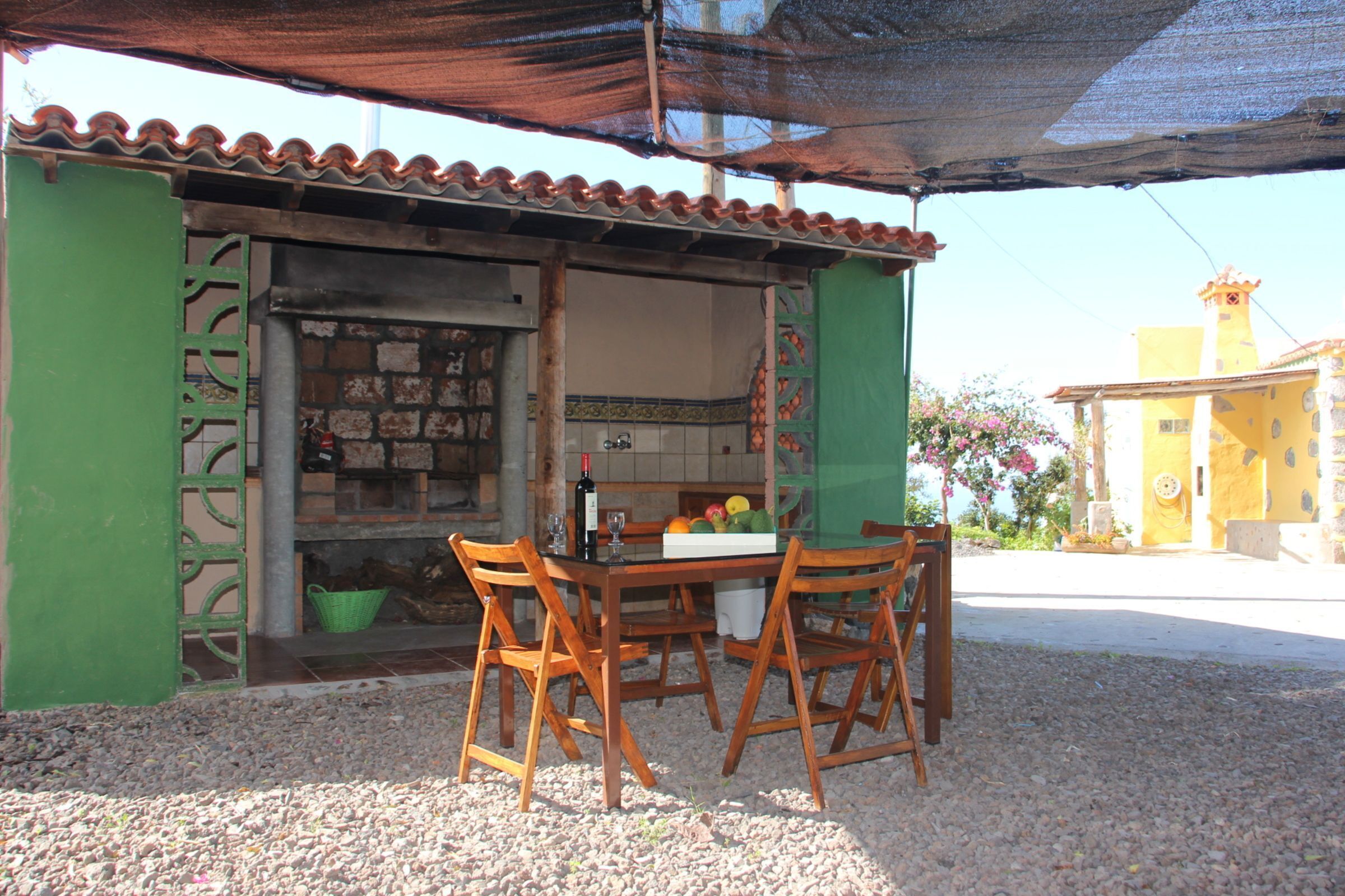 A small outdoor café with a wooden table and chairs, a tiled wall, and a green door.