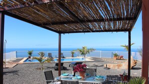 Un patio al aire libre con una mesa lista para comer, con vista a una piscina y al mar.