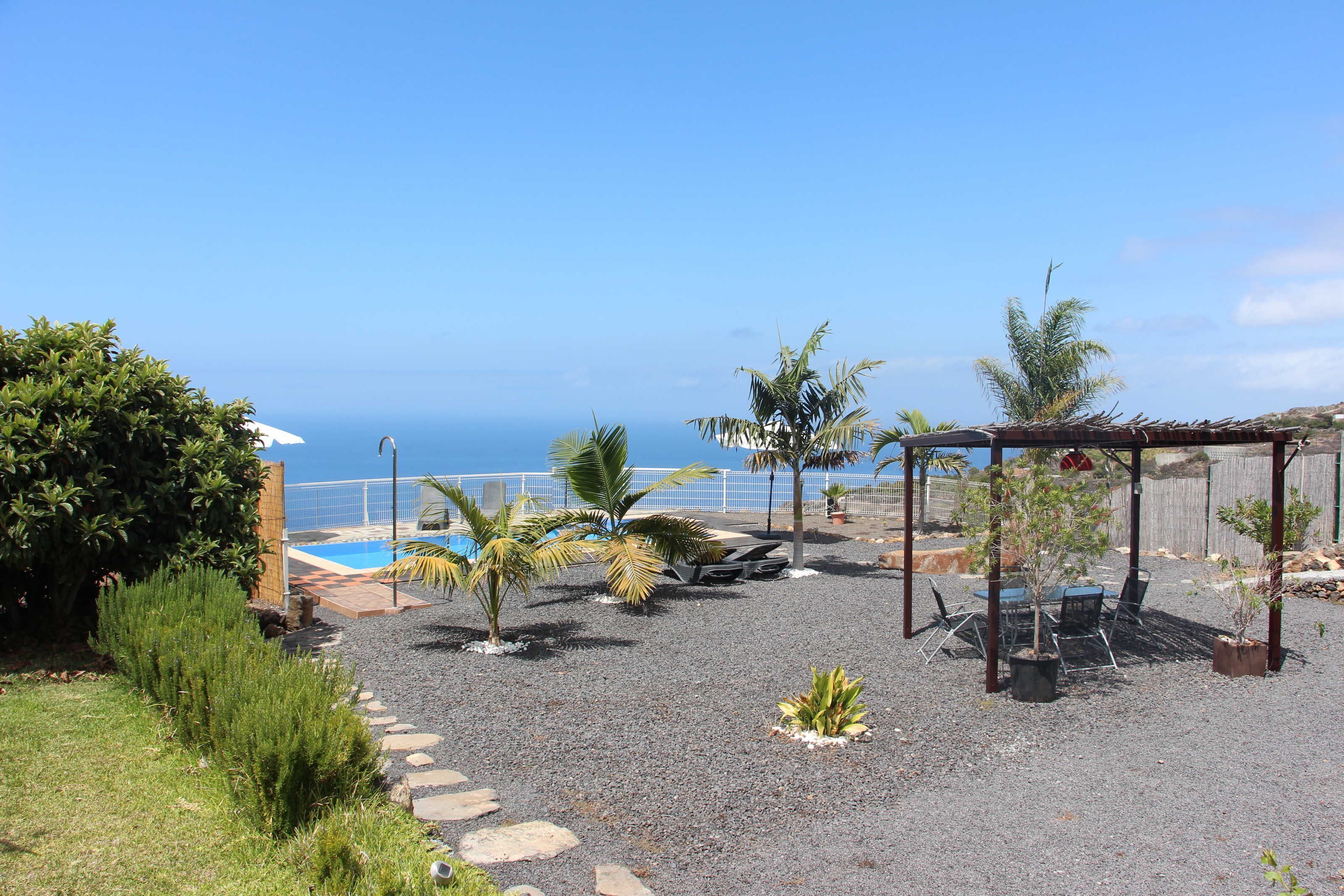 Un espace extérieur aménagé avec une piscine, des palmiers et une pergola.