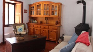 Una sala de estar con un aparador de madera, un sillón de mimbre, un sofá y una chimenea.