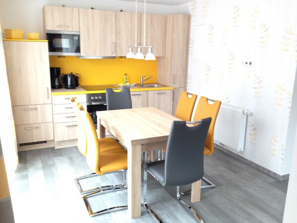 A modern kitchen with wooden cabinets, a yellow countertop, and a dining area with a wooden table and chairs.