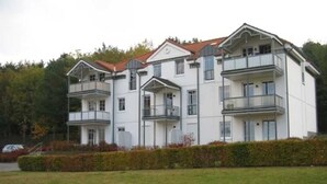 Un immeuble résidentiel à plusieurs étages, doté de balcons, d’un toit plat et d’une pelouse bien entretenue à l’avant.