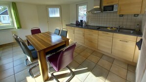 A compact kitchen with a wooden table and chairs, a microwave, and a sink.
