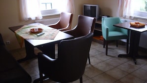 Un coin repas comprenant une table, des chaises, un téléviseur et une fenêtre avec des rideaux.