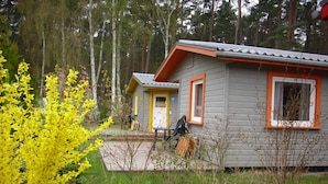 Une cabane avec un petit porche, entourée d’une forêt.
