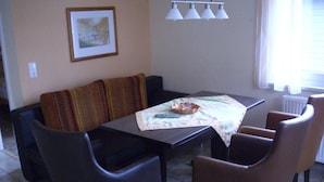 Un coin repas comprenant une table, des chaises, un canapé et un tableau encadré accroché au mur.