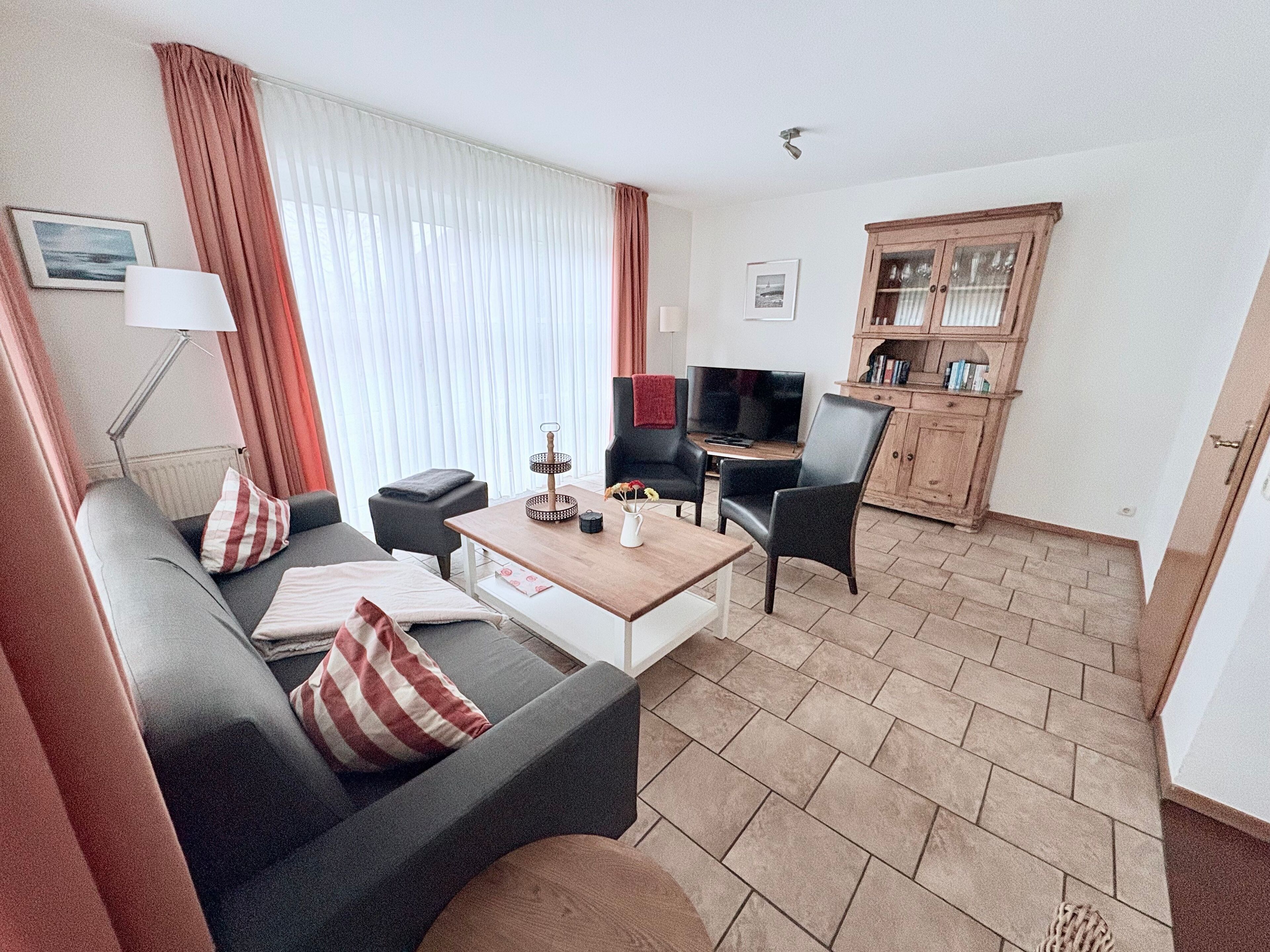A modern living room with a sofa, a coffee table, and a TV. There is a wooden cabinet and a lamp.