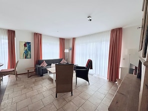 Un salon comprenant un canapé, des fauteuils, une table basse et une cheminée.