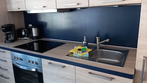 A modern kitchen with a black induction cooktop, stainless steel sink, and a built-in oven.
