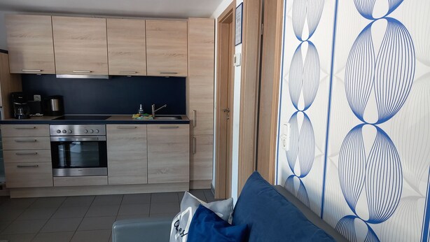 A modern kitchen with wooden cabinets, a built-in oven, and a black countertop.