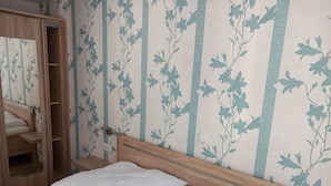 A bedroom with a wooden bed, white bedding, and a wardrobe with a mirror.