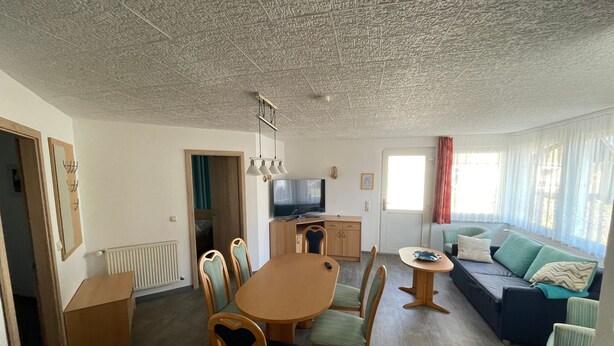 A compact living space with a dining area, a sofa, a TV, and a window with curtains. - Ferienwohnung 27, Deutschland (Trassenheide)