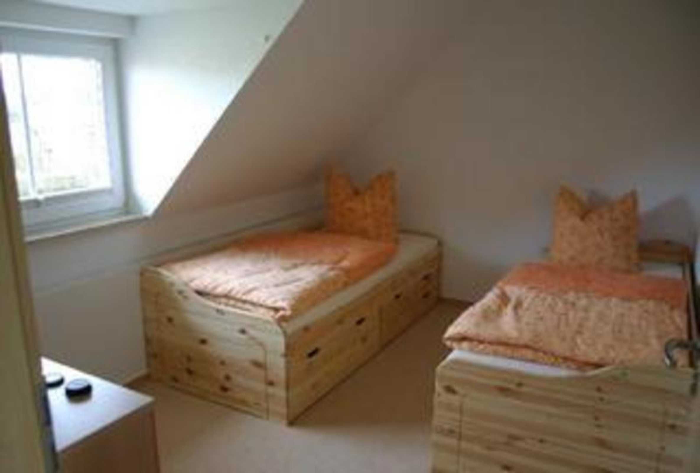 Une petite pièce triangulaire avec deux lits superposés en bois, une fenêtre et une petite table.