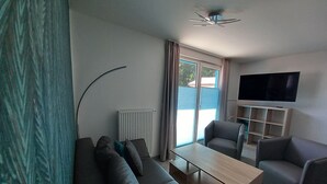 Un soggiorno moderno con un divano, poltrone, un tavolino e una TV a parete.