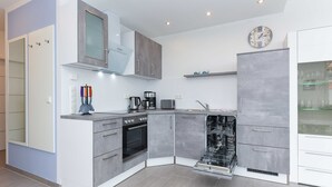Una cocina moderna con armarios grises, horno empotrado, lavavajillas y un reloj en la pared.