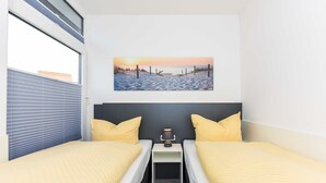 Un dormitorio con dos camas, una mesita de noche y un cuadro de una playa.